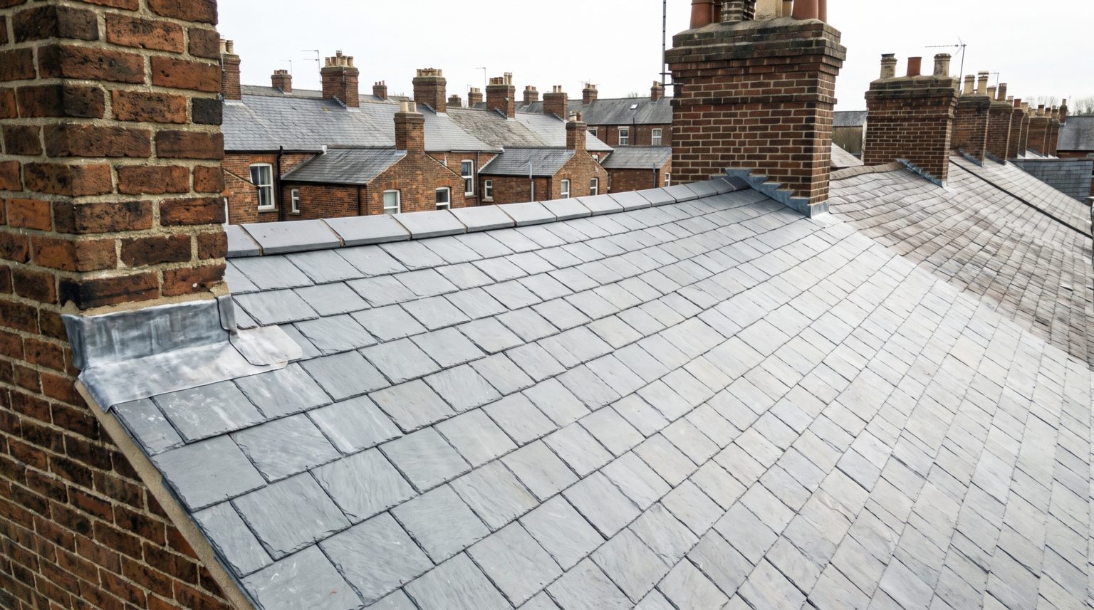Newly re-covered grey slate roof and lead-weathered chimney stack on a Victorian brick terrace
